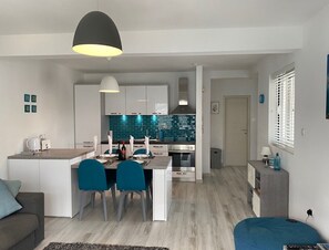 A modern kitchen with a central island, white cabinetry, and blue accents. - Stunning, fully refurbished apartment in small, exclusive complex with pool (Kotor)