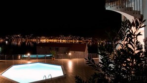 A nighttime view of a swimming pool with a cityscape in the background.