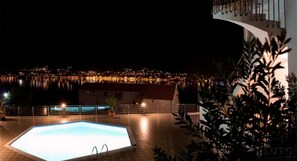 A nighttime view of a swimming pool with a cityscape in the background.