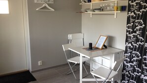 A small, modern room with a white table and chairs, a black and white patterned curtain, and a shelf with kitchen items. - Functional apartment with sea view (Tanum)