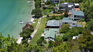 An aerial view of a coastal residential area with houses, a beach, and boats. - Private Bay Beachfront - Stunning Location! (Coromandel Township)