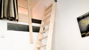 Eine Holzlade an einer weißen Wand, mit einem kleinen Fenster und einem gerahmten Bild mit Text.