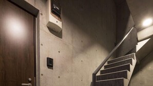 A staircase with a handrail, a wooden door, and a wall-mounted intercom. - B1  Maison Philippe Shitaya 201 (Tokyo)