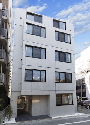 Un edificio de varios pisos con fachada plana, ventanas amplias y una entrada visible.