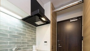 A modern kitchen with a stainless steel sink, a black range hood, and a wooden door. - B1  Maison Philippe Shitaya 201 (Tokyo)