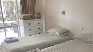 Une chambre d’hôtel avec deux lits, une commode blanche et une fenêtre avec des rideaux.