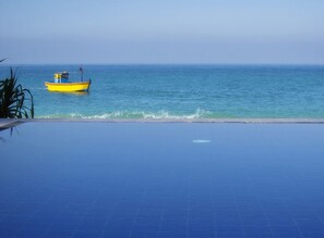 Una piscina con vista al océano y un pequeño bote.