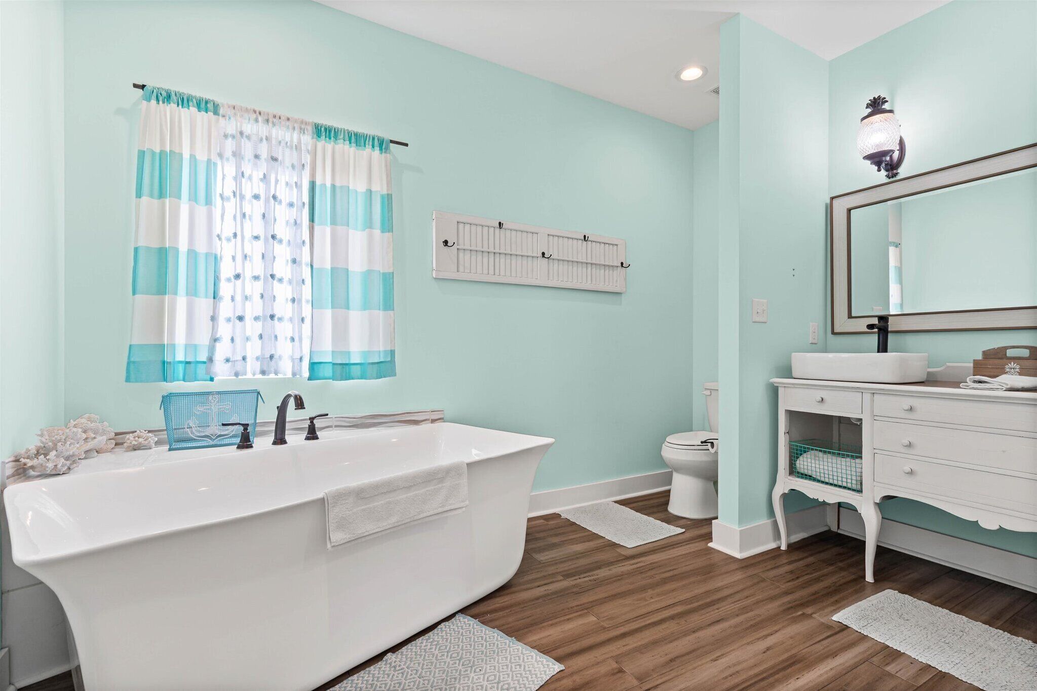A bathroom with a freestanding bathtub, a white sink, a mirror, and a toilet.