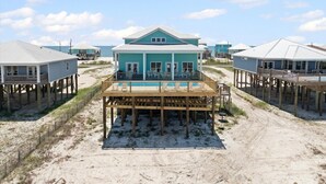 Una casa frente a la playa con un muelle de madera y una piscina.