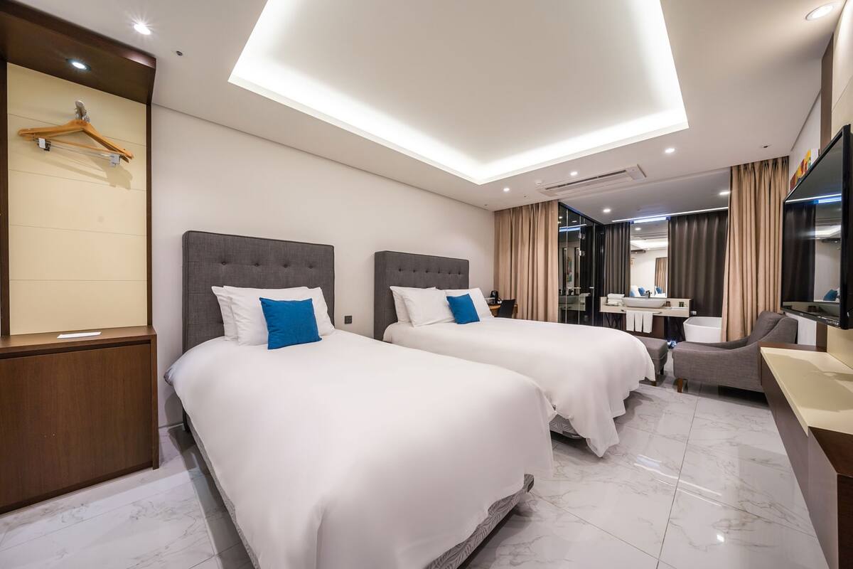 Una habitación de hotel con dos camas, un escritorio, una silla, un baño y un televisor.