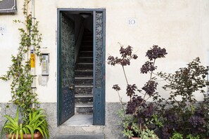 A building entrance with a metal door, a staircase, and potted plants. - Casa Rosa al Molo by Wonderful Italy (Genova)