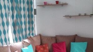Een gezellige woonkamer met een bruine hoekbank, een houten eettafel en een klein houten kastje.