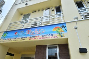 Un hotel con un cartel que indica los horarios de registro y un balcón con barandillas.