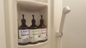 Un estante de baño con tres botellas de jabón corporal y acondicionador Il Pienta.