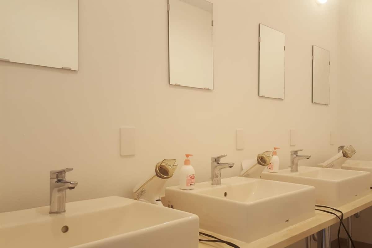 A row of three sinks with mirrors above each, in a clean and modern bathroom.
