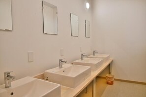 Un baño con tres lavamanos, cada uno con un espejo encima.