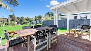 Une terrasse extérieure dotée d’une plateforme en bois, d’un espace salon couvert et offrant une vue sur un quartier résidentiel.