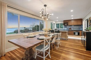 A modern kitchen with a wooden dining table and chairs, large windows, and a view of the outdoors. - Lakefront Rotorua in Town (Rotorua Township)
