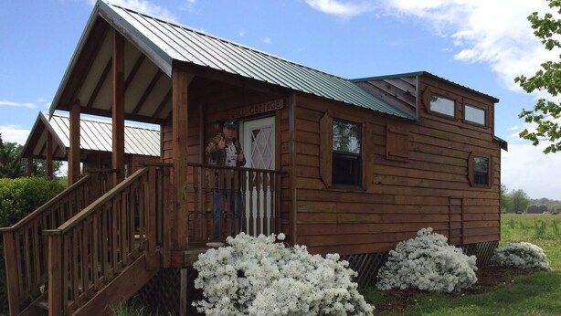 A wooden cabin with a porch and a staircase leading up to it.