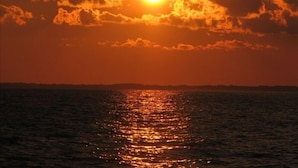 A sunset over a body of water with a clear sky and clouds.