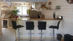 A modern kitchen with a bar area, white walls, and a wooden ceiling.