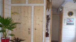 A wooden interior with a table, two potted plants, a kettle, and a door with a sign indicating a seafood restaurant.