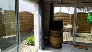 Uma área de pátio com deck de madeira, churrasqueira e mesa com cadeiras.