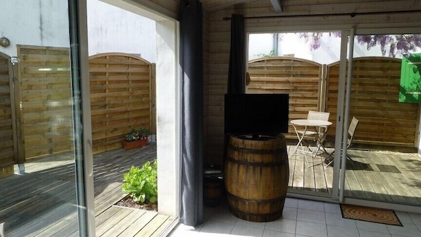 A patio area with a wooden deck, a barbecue grill, and a table with chairs.