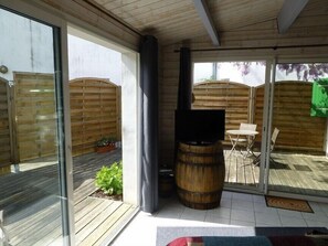 A patio area with a wooden deck, a barbecue grill, and a table with chairs.