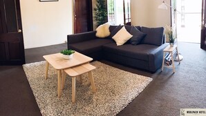 A living room with a dark sofa, a small wooden table, and a large rug.