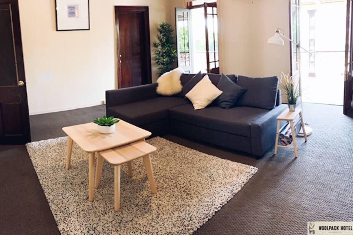 A living room with a dark sofa, a small wooden table, and a large rug.