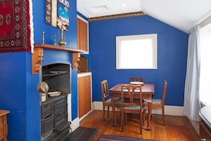 Un coin repas avec une table et des chaises en bois, un four encastré et un mur bleu.