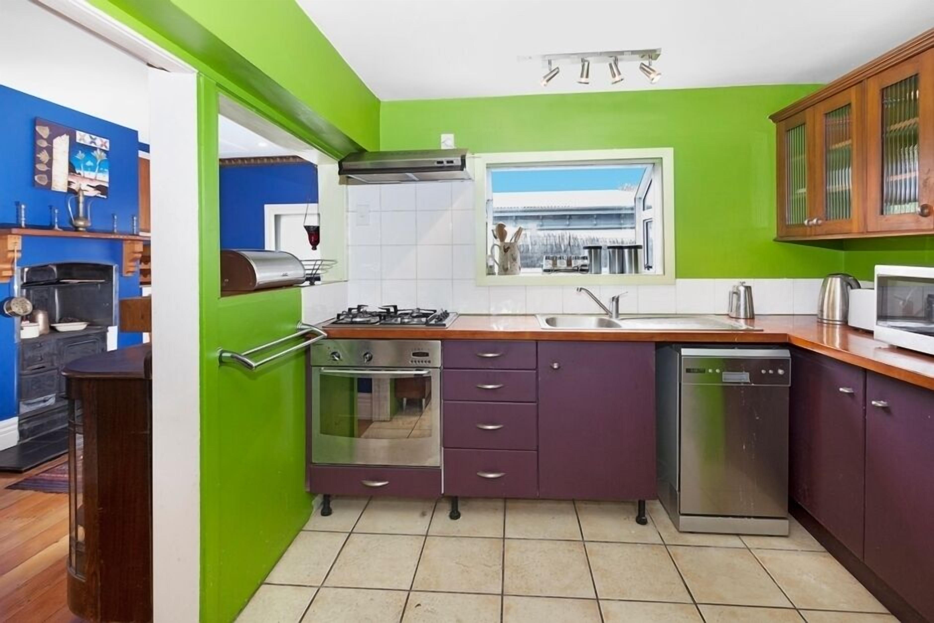 Een compacte keuken met een gasfornuis, oven, vaatwasser en een raam met uitzicht.