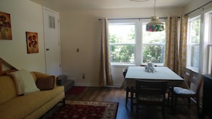A dining area with a table and chairs, a sofa, and a window with curtains. - Cabin by the river, room to roam. Close access to all the best. 30+ days (Ridgway)