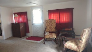 A room with a door, two chairs, a small table, and a lamp. - Cabin by the river, room to roam. Close access to all the best. 30+ days (Ridgway)