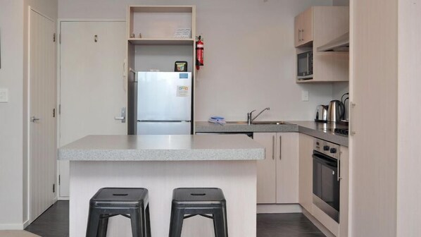 A modern kitchen with a central island, stainless steel appliances, and a microwave.