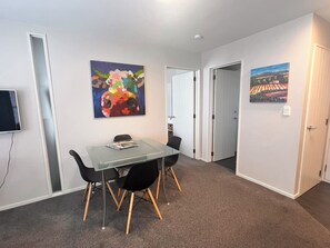 A conference room with a glass table, black chairs, and two paintings on the walls.