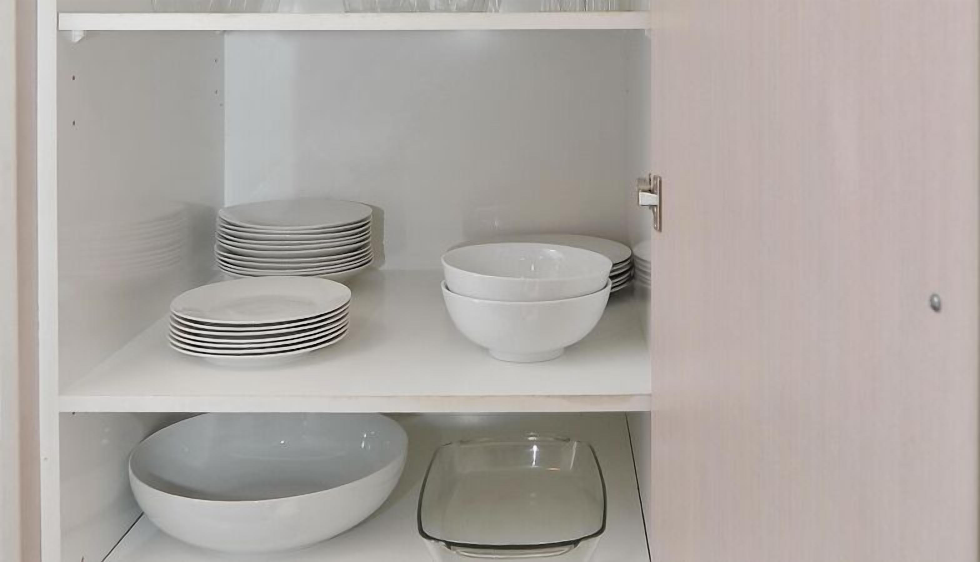 A white cabinet with multiple white plates and bowls.