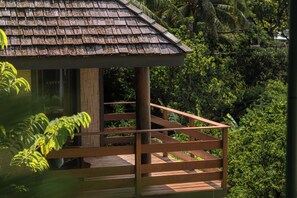 A wooden deck with a railing, surrounded by lush greenery.
