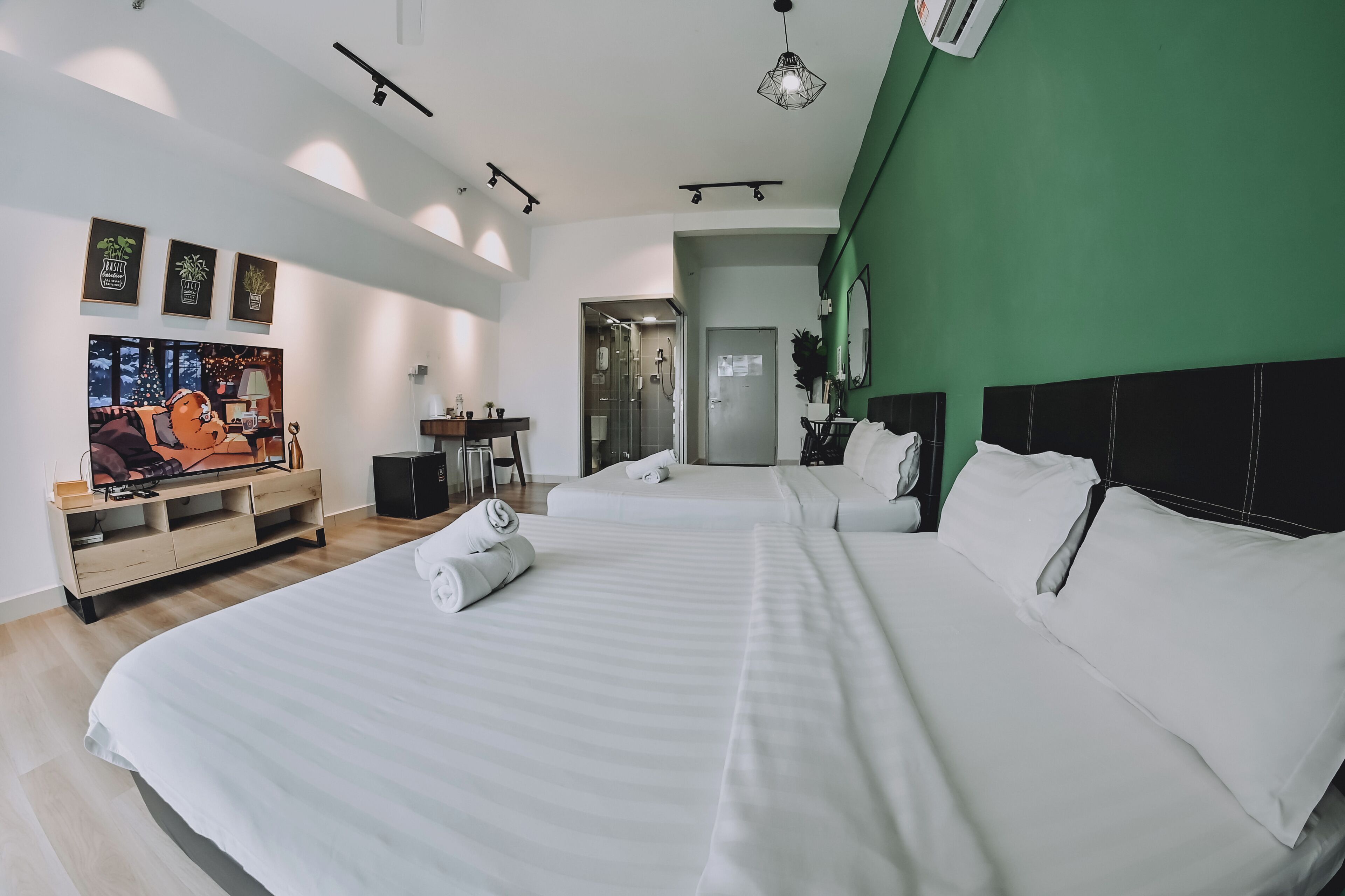 A modern hotel room with a large bed, a desk with a chair, and a green accent wall.