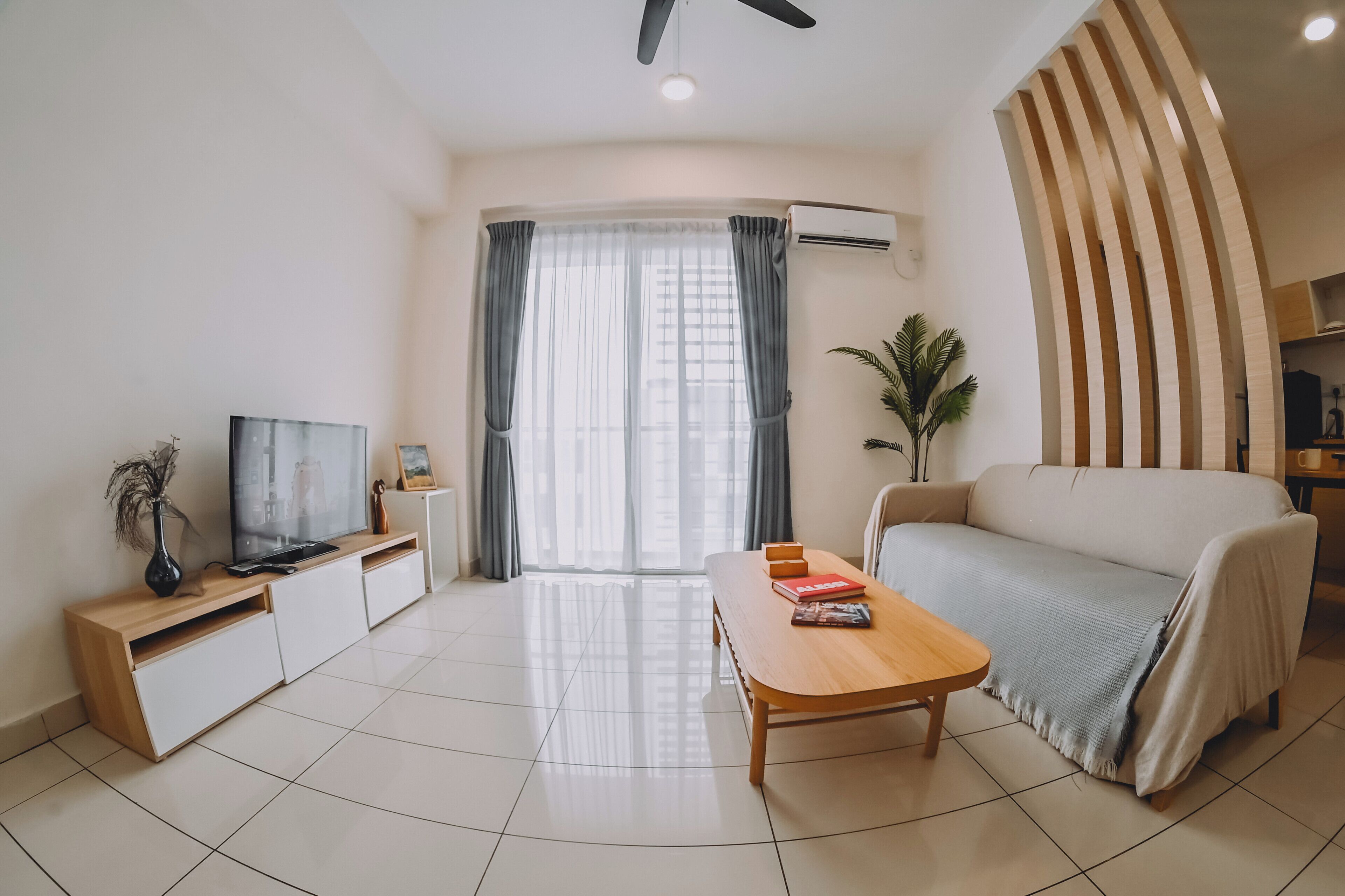 Una sala de estar moderna con sofá, televisor, una mesa de centro de madera y un comedor.