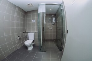 Une salle de bain moderne dotée d’une douche à parois de verre, de toilettes et d’un lavabo.
