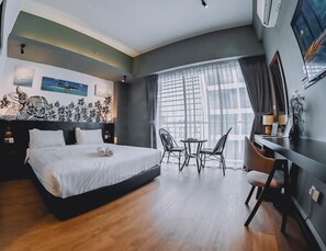 Une chambre d’hôtel moderne dotée d’un grand lit, d’un bureau avec deux chaises, d’une grande fenêtre avec des rideaux et d’œuvres d’art accrochées aux murs.