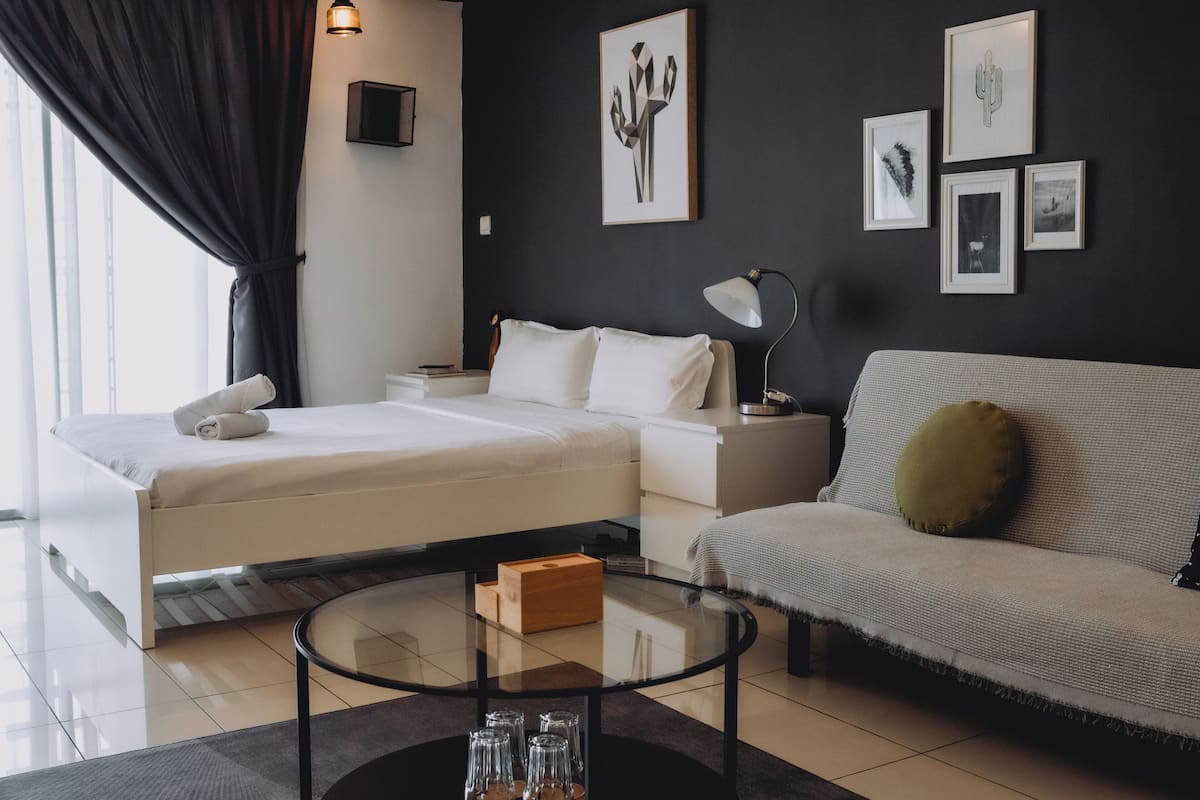 Ein modernes Hotelzimmer mit einem Bett, einem Sofa, einem Glastisch und Kunstwerken an den Wänden.