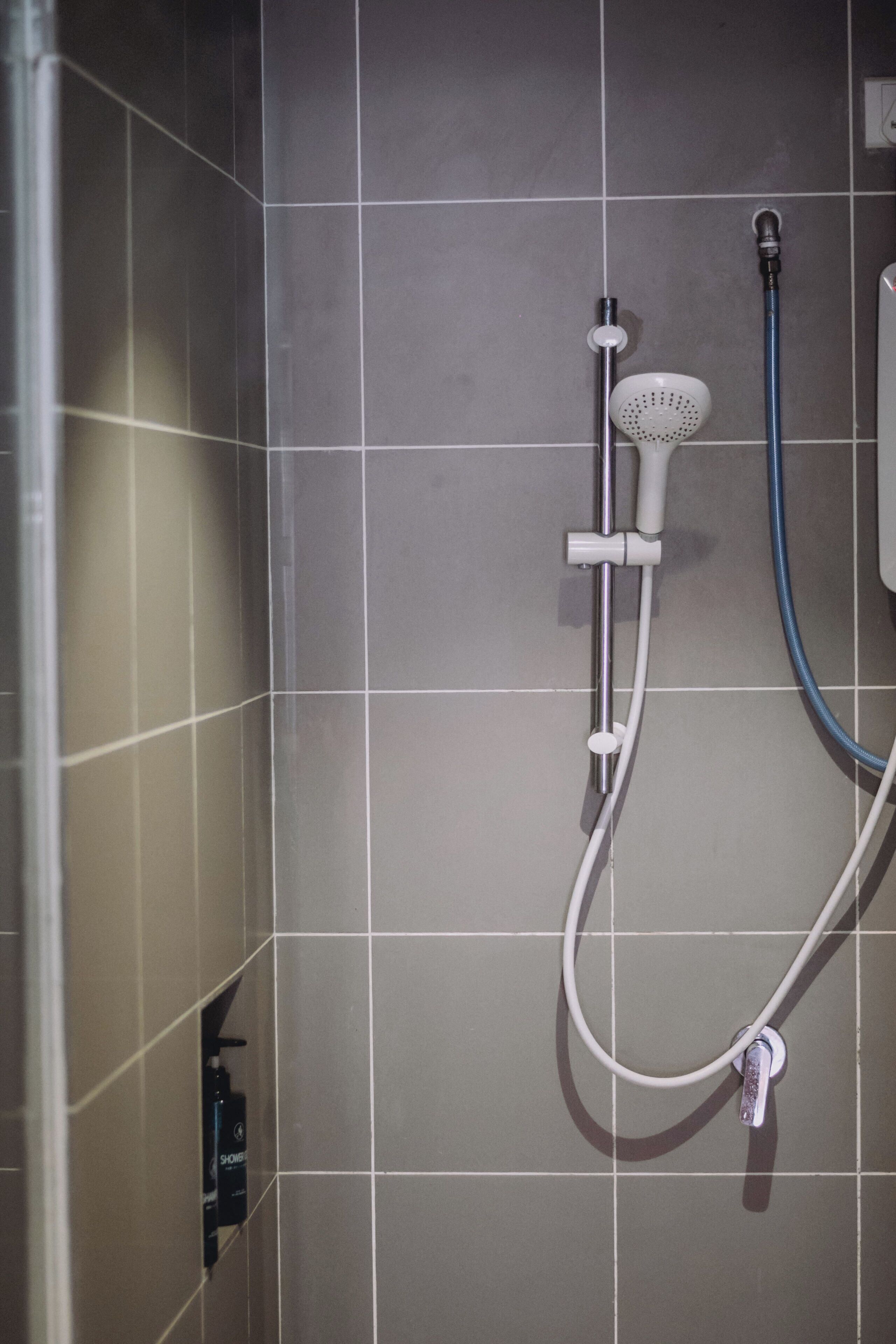 Un espace douche équipé d’un pommeau de douche à main et d’un flexible.