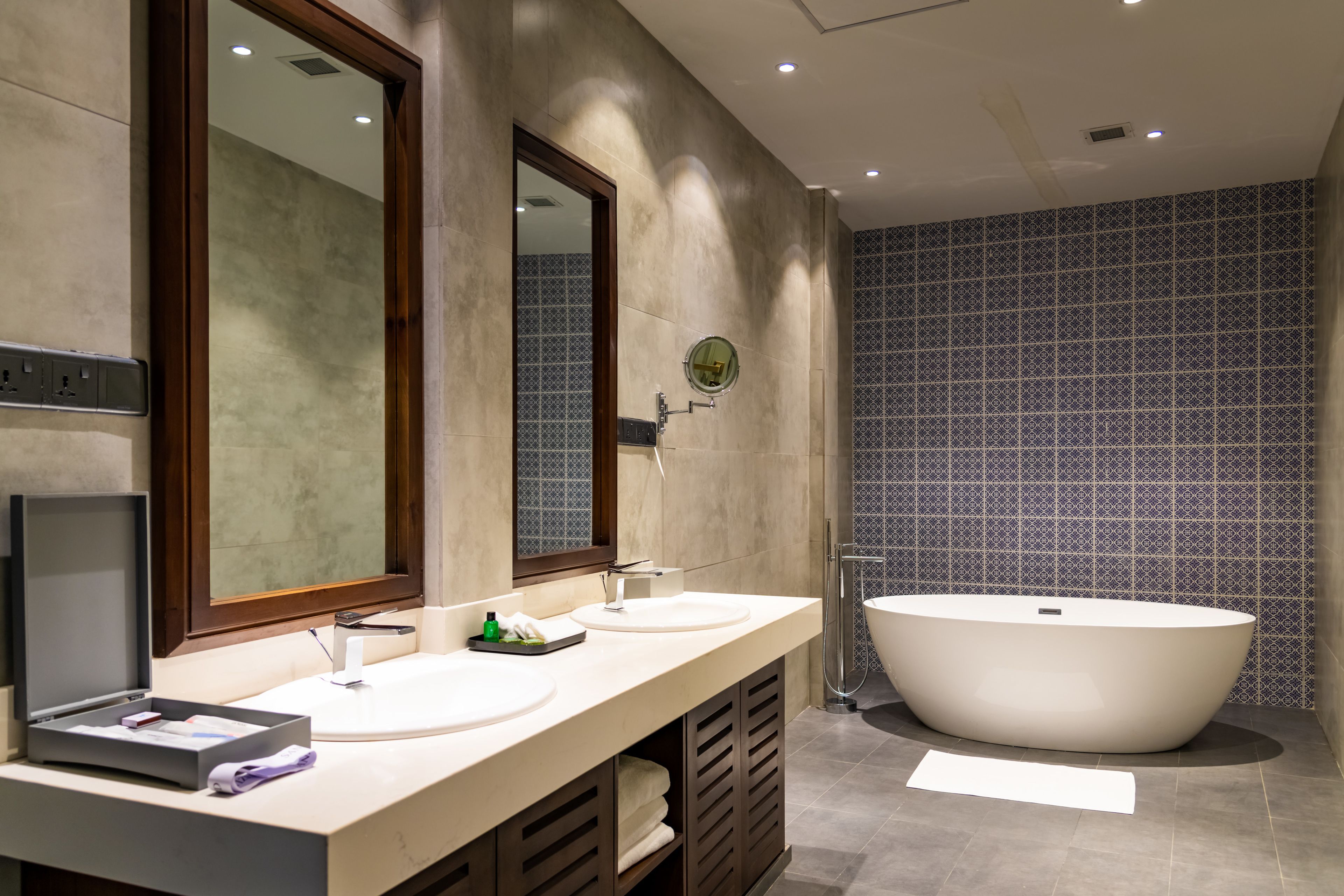 A modern bathroom with two sinks, a large bathtub, and a mirror.