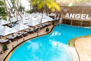 Una piscina al aire libre, sombrillas, sillones reclinables de piscina