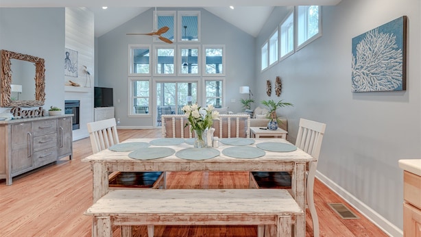 A spacious dining area with a high ceiling, large windows, and a view of the outdoors.