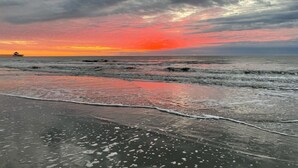 A beach with waves and a sunset.