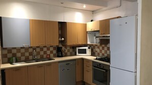 Una cocina compacta con gabinetes de madera, lavavajillas, microondas, estufa y refrigerador.